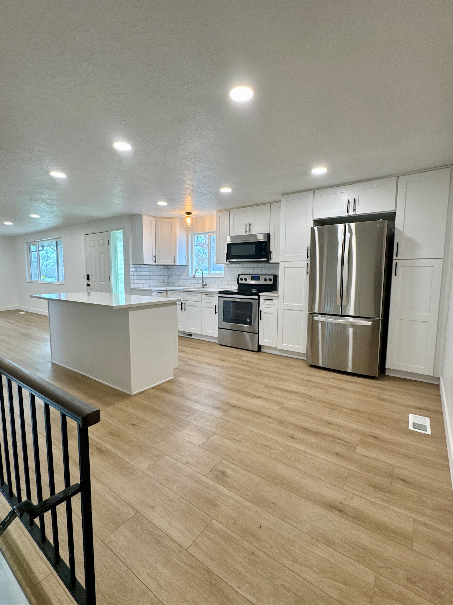 Kitchen featuring white cabinets, light wood-style flooring, stainless steel appliances, recessed lighting, and light countertops