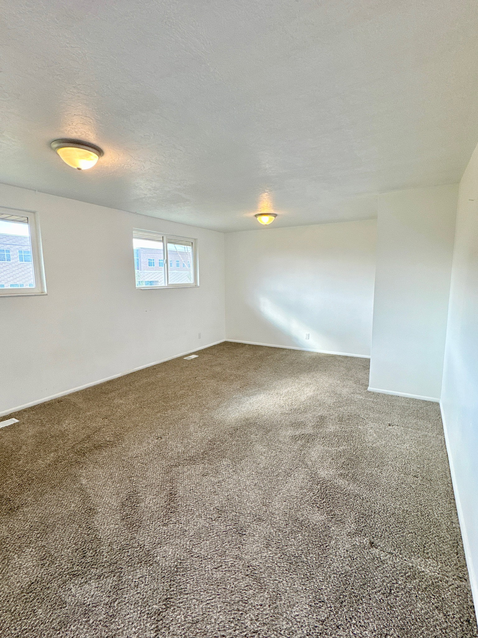 Carpeted empty room featuring a textured ceiling and baseboards