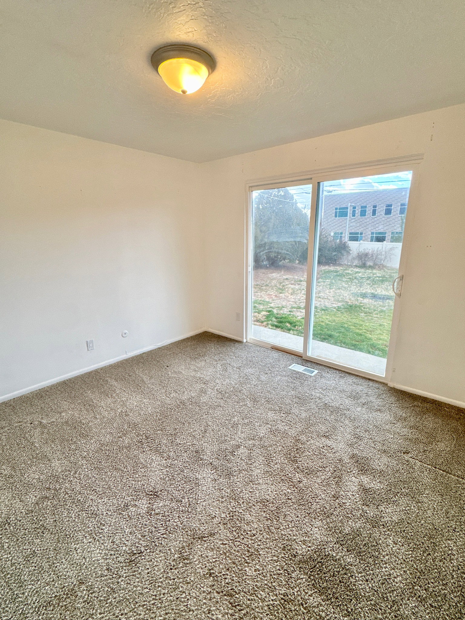 Carpeted empty room featuring a textured ceiling and baseboards