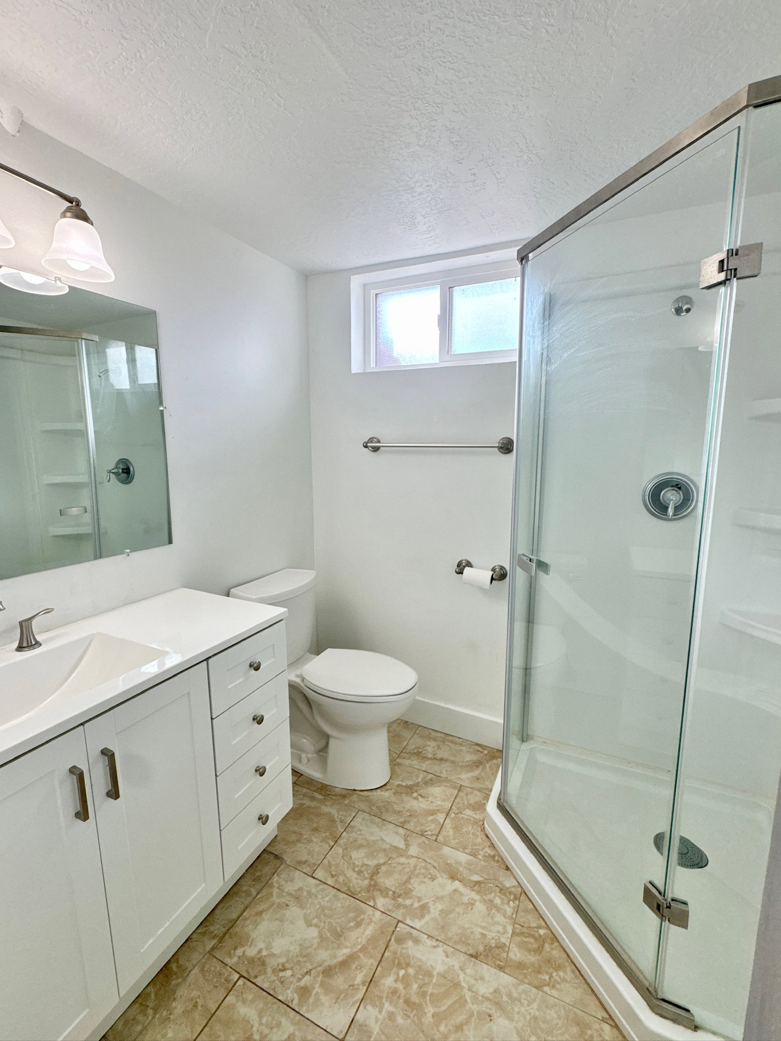 Full bath with a shower stall, vanity, and a textured ceiling