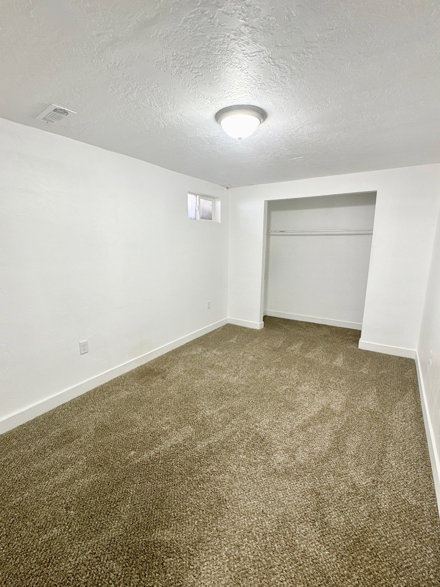 Unfurnished bedroom featuring dark colored carpet, a textured ceiling, and a closet