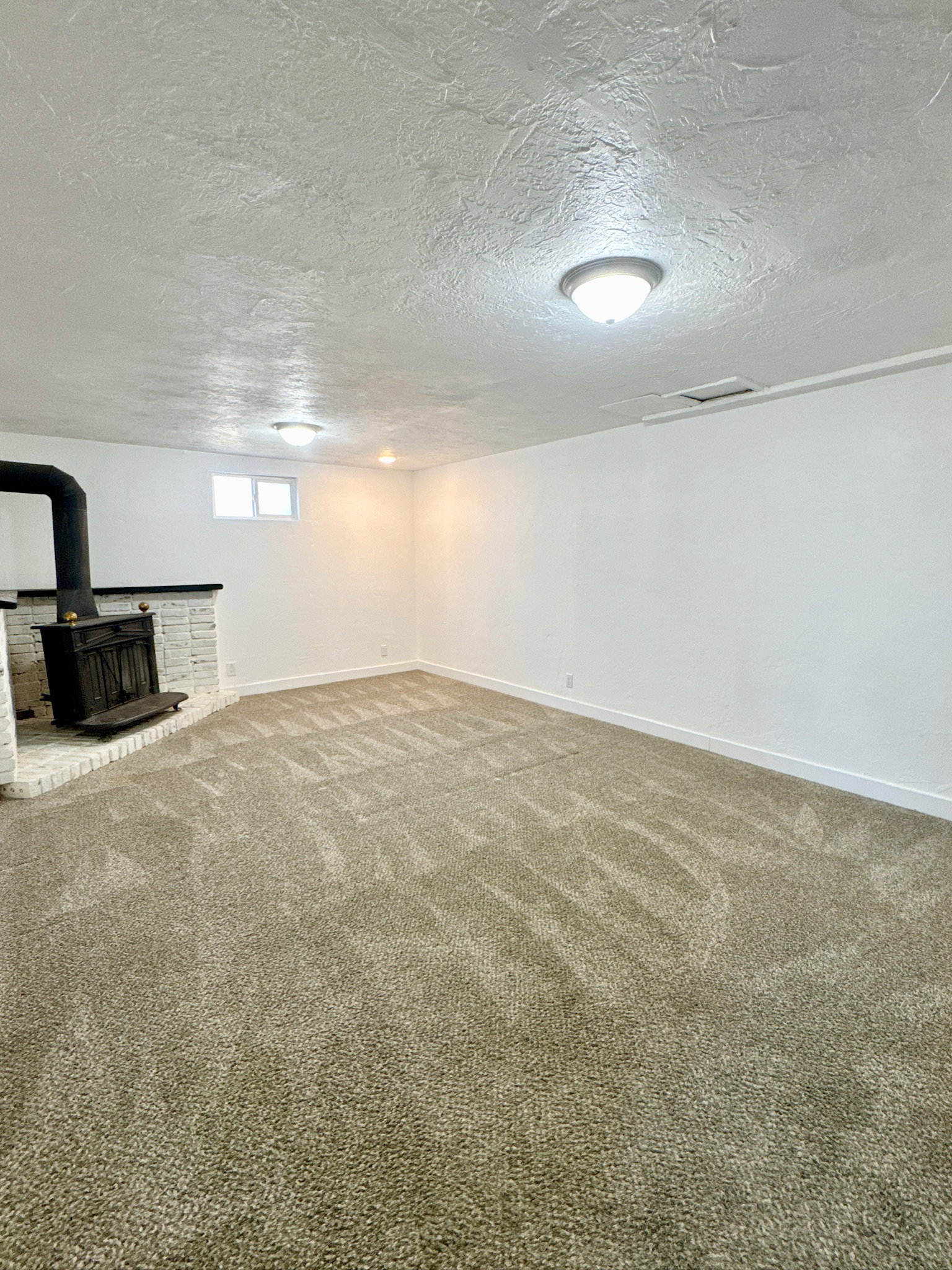 Basement featuring a wood stove, carpet floors, and a textured ceiling