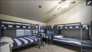 Bedroom with vaulted ceiling, light colored carpet, and ceiling fan