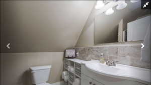 Half bathroom featuring vanity and vaulted ceiling