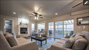 Living room featuring a ceiling fan, wood finished floors, recessed lighting, a tiled fireplace, and a baseboard radiator