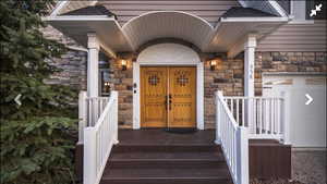 View of exterior entry with stone siding and a porch