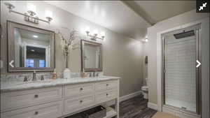Bathroom featuring double vanity, a shower stall, and dark wood-style floors
