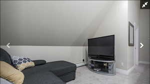 Carpeted living area with vaulted ceiling and a baseboard radiator