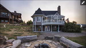 Back of house featuring a patio area, a deck, an outdoor fire pit, a chimney, and french doors