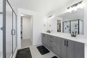 Bathroom with a spacious closet, a stall shower, double vanity, and light tile patterned floors