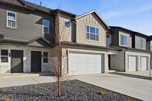 Craftsman-style house with stone siding, board and batten siding, concrete driveway, and an attached garage