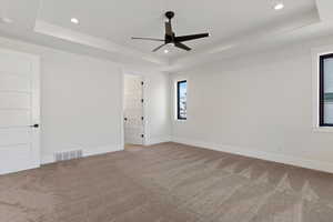 Unfurnished room with a raised ceiling, carpet floors, a ceiling fan, and recessed lighting