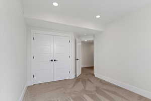 Unfurnished bedroom with light colored carpet, a closet, and recessed lighting