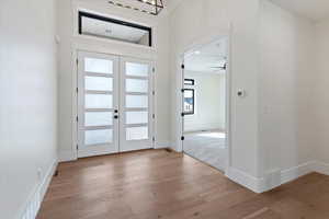 Entryway featuring light wood-style floors, french doors, and suspended lighting