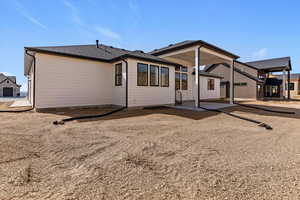 Rear view of house featuring a patio area and a shingled roof