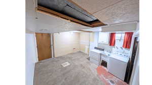 Laundry room with light colored carpet, white cabinets, utility sink, washing machine and clothes dryer