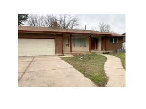 Ranch-style house featuring a porch, a garage, driveway, roof with shingles, and brick siding
