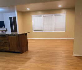 Kitchen  looking into living room area featuring light wood finished floors, granite  island counters with drawers, and shelf , and recessed lighting
