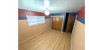 Unfurnished bedroom with light wood finished floors, a closet, and a textured ceiling