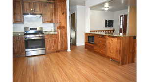 Kitchen featuring stainless steel appliances, granite counters, light wood finished floors, and wood finish shaker cabinets