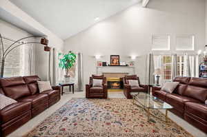 Living area with a tiled fireplace, vaulted ceiling, and light colored carpet