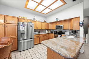 Kitchen with stainless steel appliances, a peninsula, tasteful backsplash, light stone counters, and light tile patterned flooring