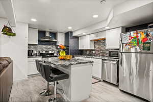 Kitchen featuring stainless steel appliances, a kitchen bar, white cabinets, a center island, and dark stone countertops