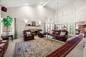 Living area featuring light colored carpet, a tiled fireplace, and suspended lighting