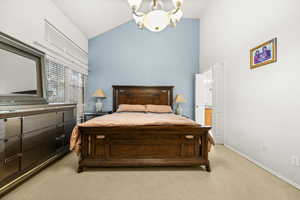 Bedroom with vaulted ceiling, carpet flooring, and suspended lighting