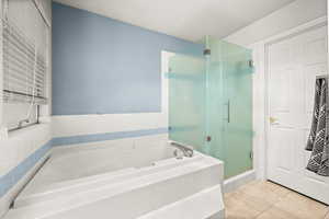 Bathroom with a shower stall, a bath, and light tile patterned floors