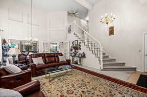Living room with suspended lighting, a high ceiling, and ceiling fan