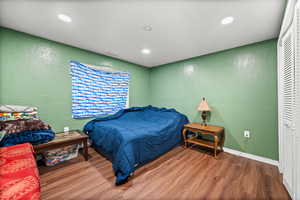 Bedroom featuring a textured wall, wood finished floors, and recessed lighting