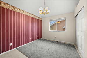 Unfurnished bedroom featuring suspended lighting, a closet, light carpet, and an accent wall