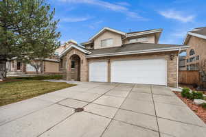 Traditional-style home with driveway, roof with shingles, brick siding, and a front yard