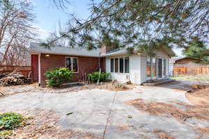 Rear view of house with brick siding, a chimney, a patio, and roof with shingles
