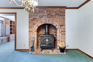 Detailed view of ornamental molding, carpet, suspended lighting, and a wood stove