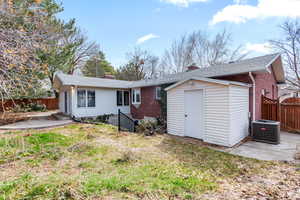 Back of property with a fenced backyard, brick siding, and a storage unit