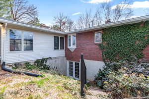View of side of property featuring a chimney and brick siding