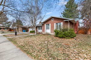 Ranch-style home featuring brick siding, a garage, a chimney, and driveway