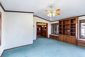 Unfurnished living room with crown molding, ceiling fan, and light colored carpet