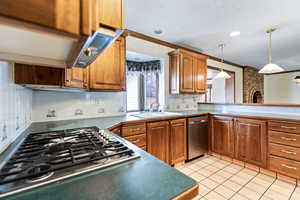 Kitchen featuring wood finish cabinets, decorative backsplash, ornamental molding, stainless steel appliances, and light tile patterned floors