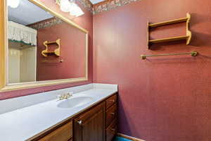 Full bathroom with vanity and wallpapered walls