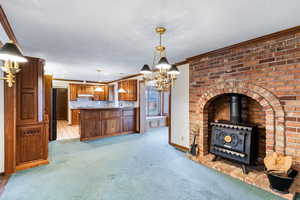 Kitchen featuring ornamental molding, wood finish cabinets, light carpet, a chandelier, and a peninsula