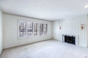 Unfurnished living room with carpet floors, a fireplace with flush hearth, and a textured ceiling