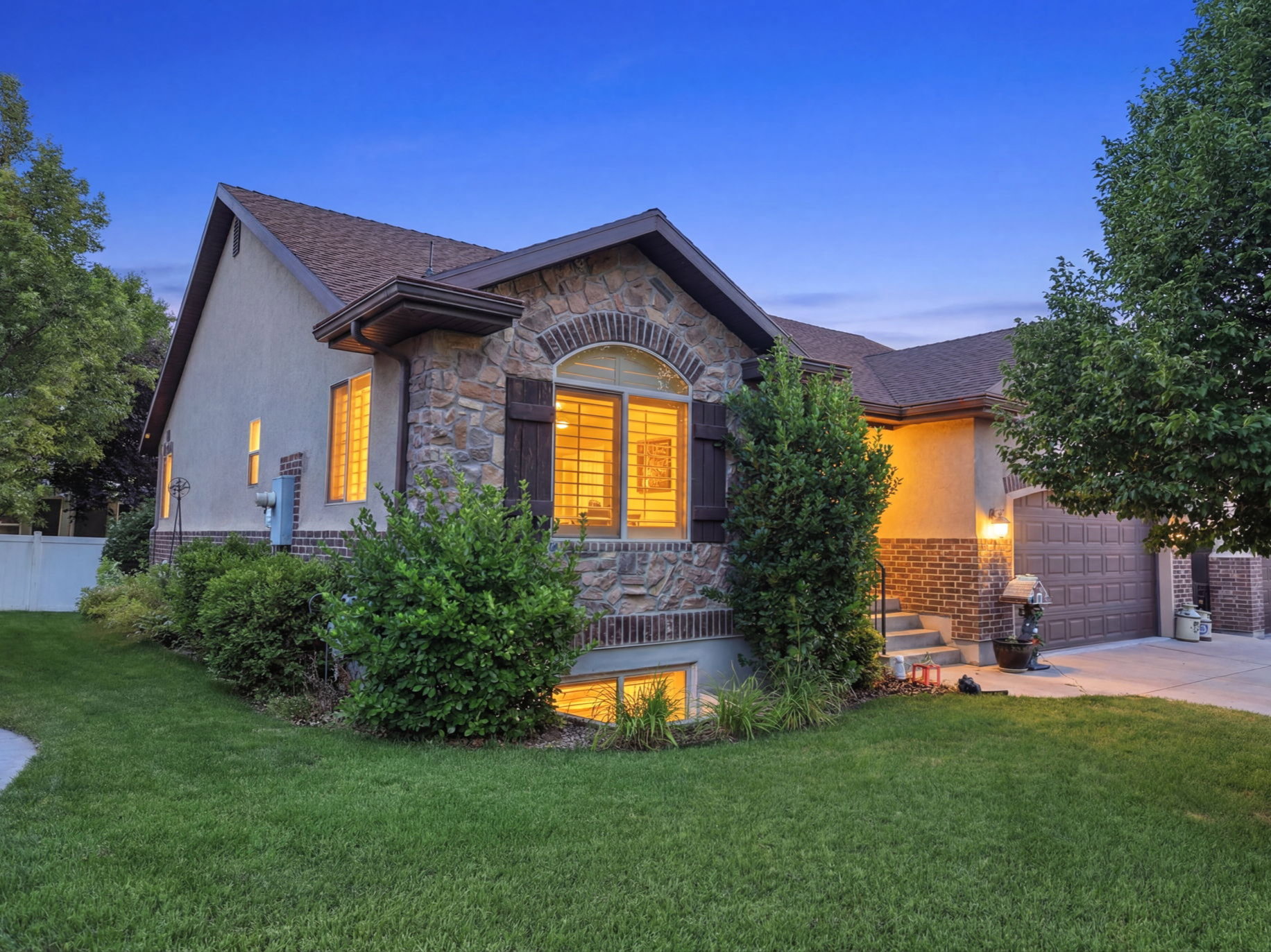 Stone and stucco facade featuring a prominent arched window with plantation shutters