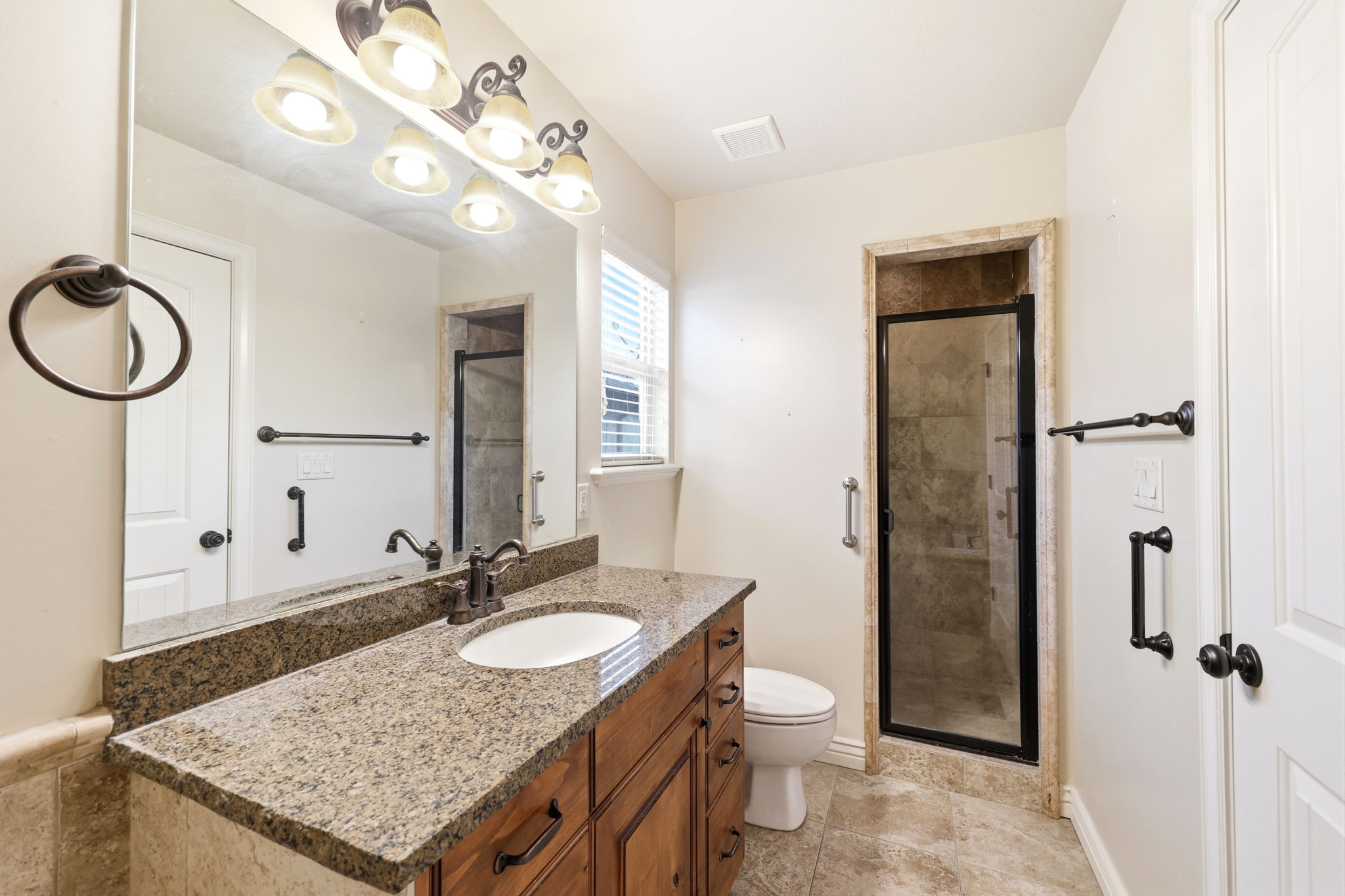 Bathroom with a granite-top vanity, an undermount sink, and dark wood-finish cabinetry