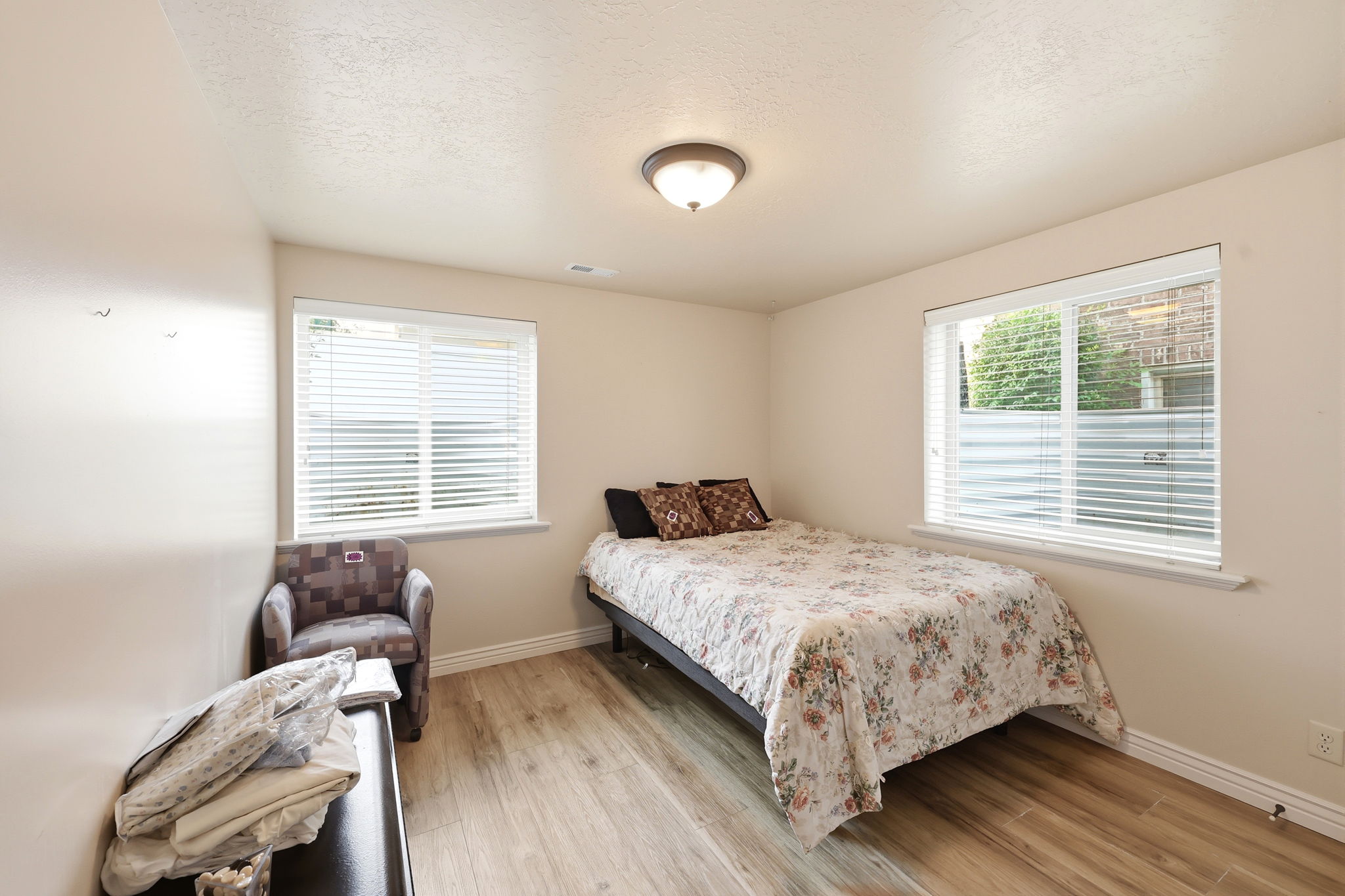Room featuring two windows with white blinds, wood-finish flooring, and a flush-mount ceiling light fixture