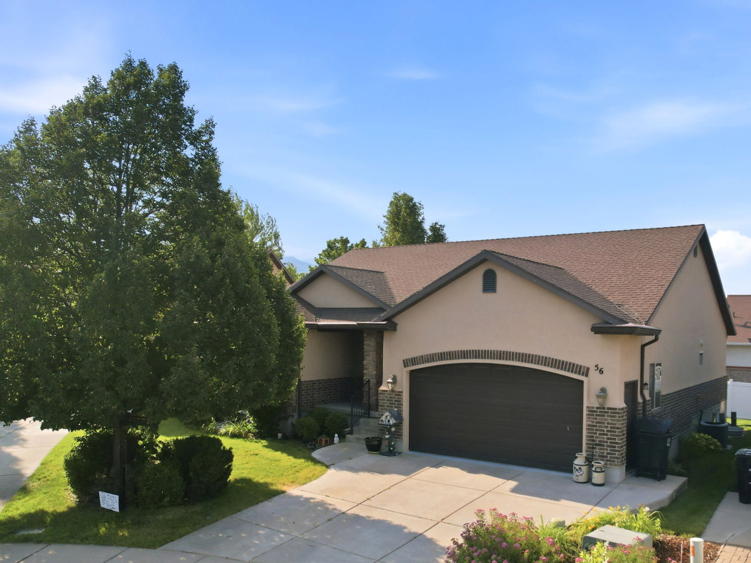 Stucco exterior with stone accents and a brown shingle roof