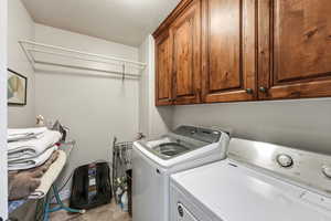 Laundry area featuring cabinet space, washing machine and dryer, and a textured ceiling