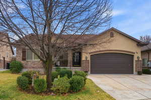 View of front facade with an attached garage, concrete driveway, brick siding, and stucco siding